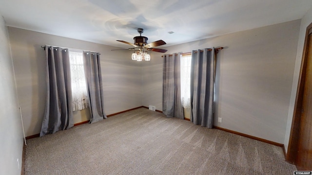 carpeted spare room featuring a healthy amount of sunlight and ceiling fan