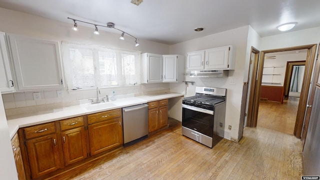 kitchen with sink, light wood-type flooring, appliances with stainless steel finishes, decorative backsplash, and white cabinets