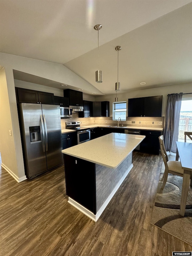 kitchen with appliances with stainless steel finishes, pendant lighting, sink, dark hardwood / wood-style flooring, and a center island