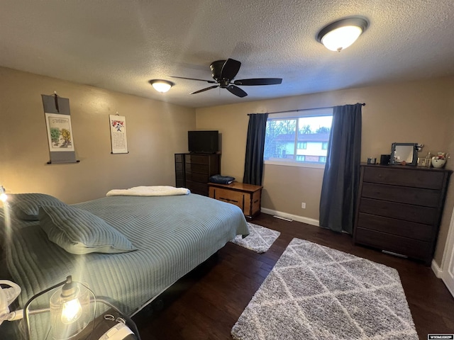 bedroom featuring ceiling fan, dark hardwood / wood-style floors, and a textured ceiling