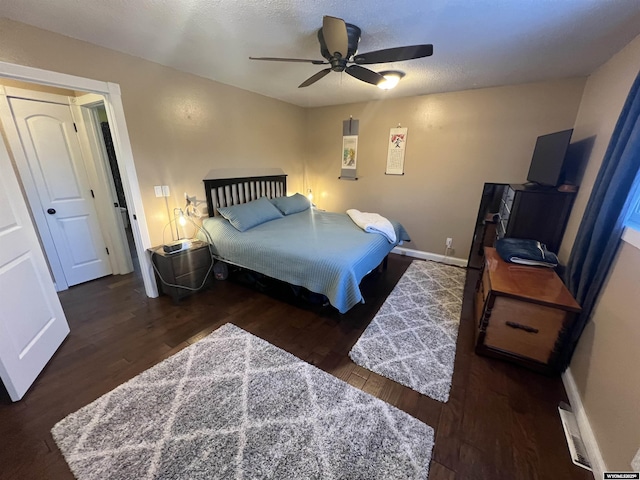 bedroom with ceiling fan, dark wood-type flooring, and a textured ceiling