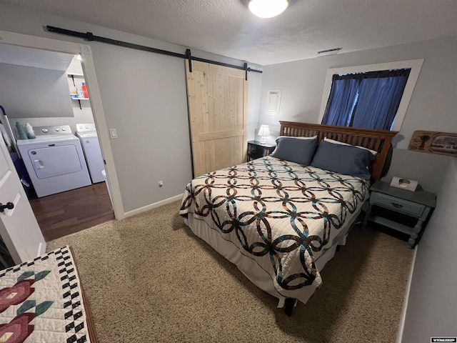 bedroom featuring a barn door, washing machine and clothes dryer, and a textured ceiling