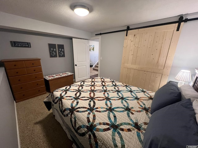 carpeted bedroom with a barn door and a textured ceiling