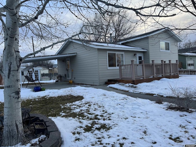 snow covered house featuring a wooden deck