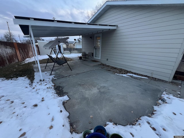 snow covered patio featuring a carport