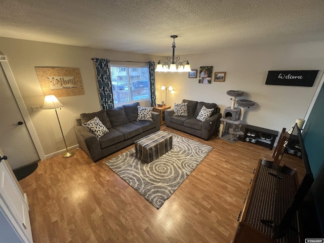 living room featuring wood-type flooring, a textured ceiling, and a notable chandelier