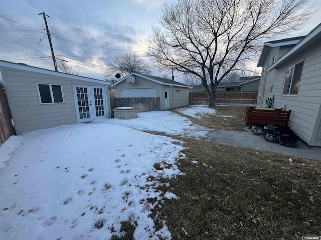 yard layered in snow featuring a garage and an outdoor structure