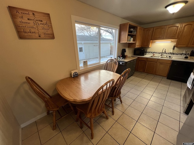 kitchen featuring sink, light tile patterned floors, and black appliances