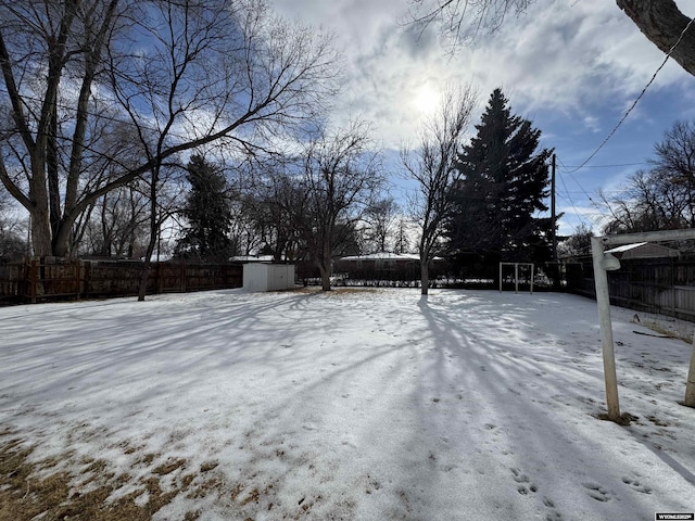 yard covered in snow with a fenced backyard, an outdoor structure, and a shed