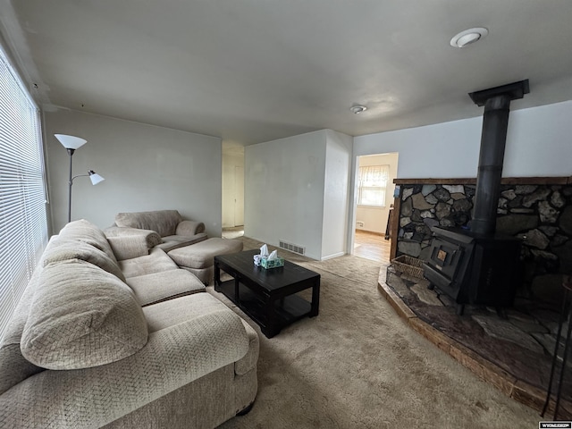 living area featuring visible vents, a wood stove, and carpet flooring