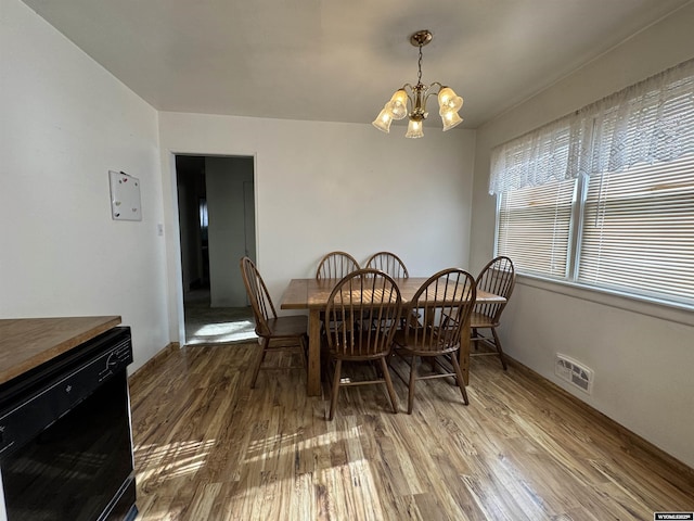 dining space with hardwood / wood-style floors and a notable chandelier