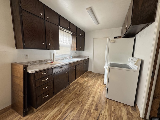 kitchen featuring sink, dark brown cabinets, white refrigerator, light hardwood / wood-style floors, and washer / dryer