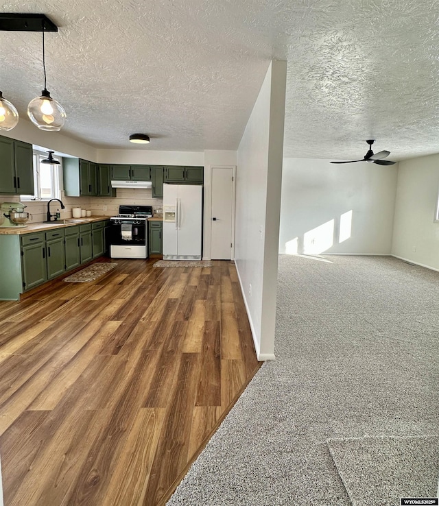 kitchen featuring sink, green cabinets, hanging light fixtures, white fridge with ice dispenser, and range with gas cooktop