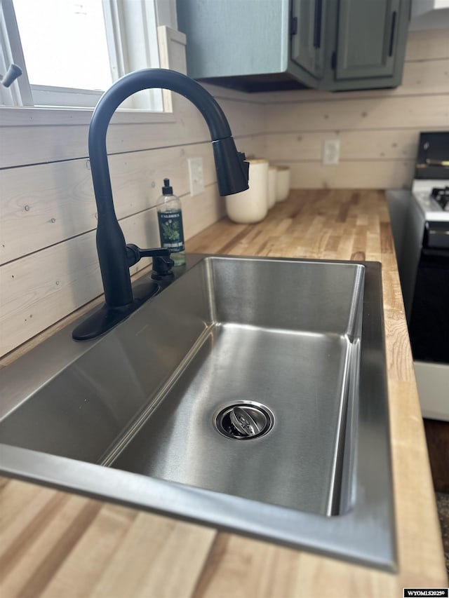 details with butcher block counters, sink, range, and wood walls