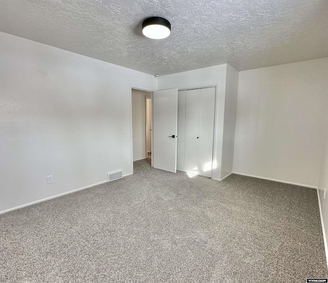 unfurnished bedroom with carpet floors, a closet, and a textured ceiling