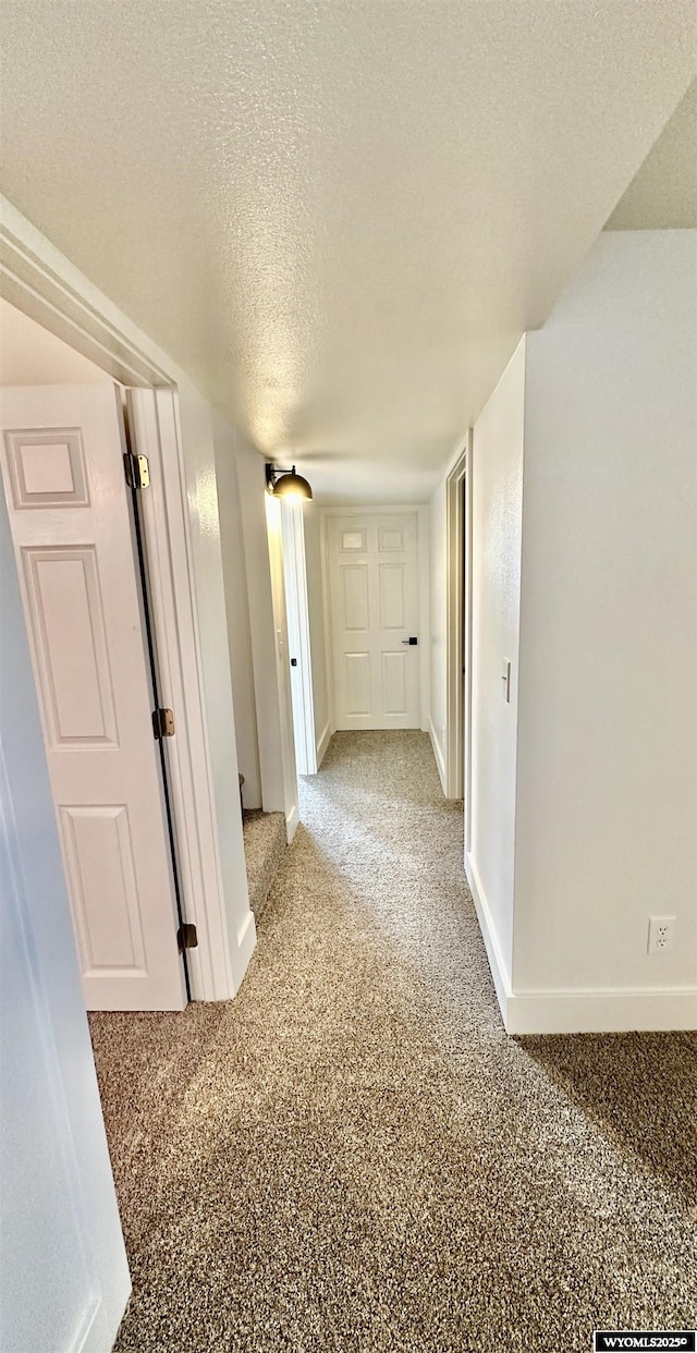 corridor featuring light colored carpet and a textured ceiling