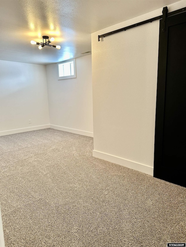 basement with carpet flooring, a barn door, and a textured ceiling