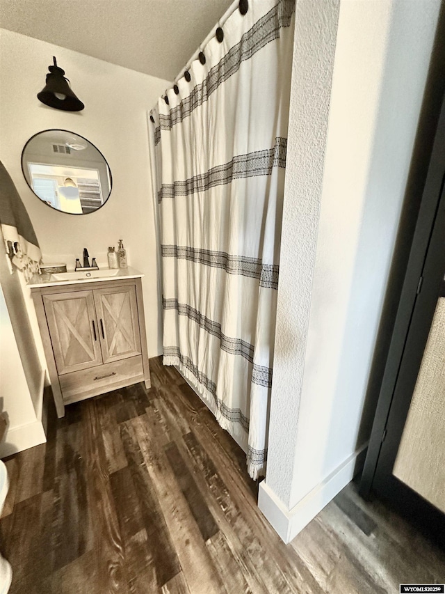 bathroom with hardwood / wood-style flooring, vanity, and a textured ceiling