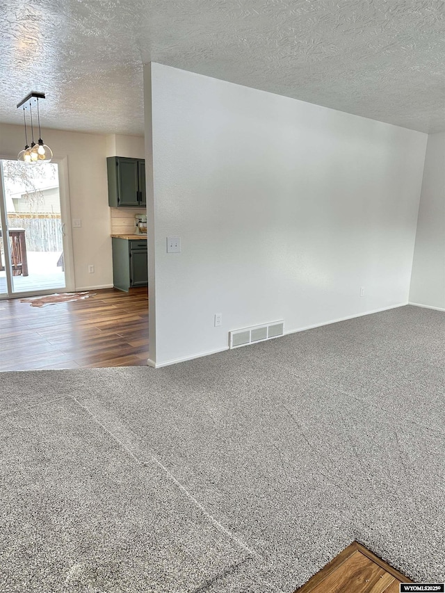 carpeted empty room with a textured ceiling