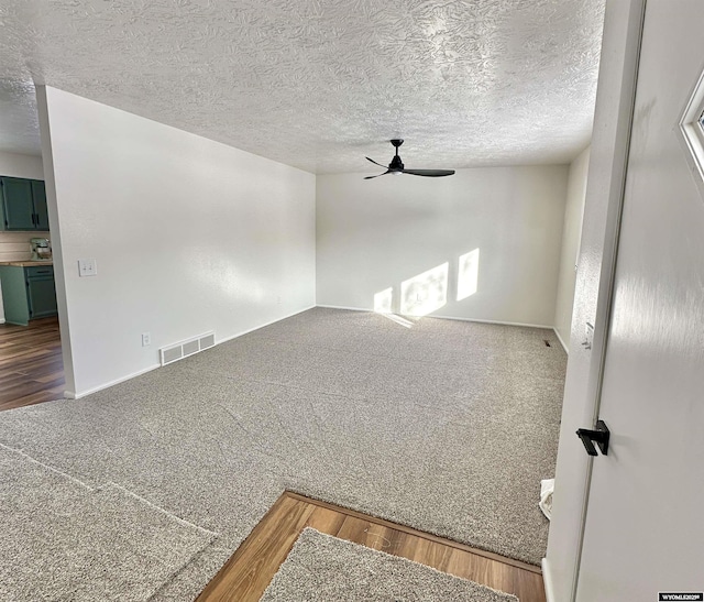 unfurnished room featuring ceiling fan, carpet flooring, and a textured ceiling