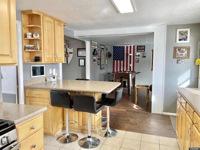 kitchen featuring a breakfast bar area, light brown cabinets, and light tile patterned floors