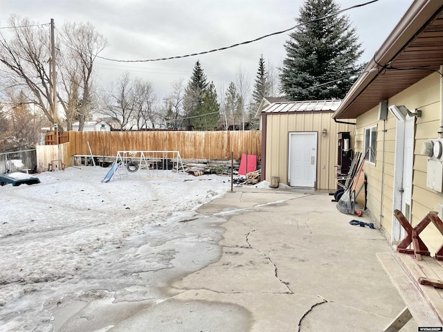 snow covered patio with a trampoline and a storage unit