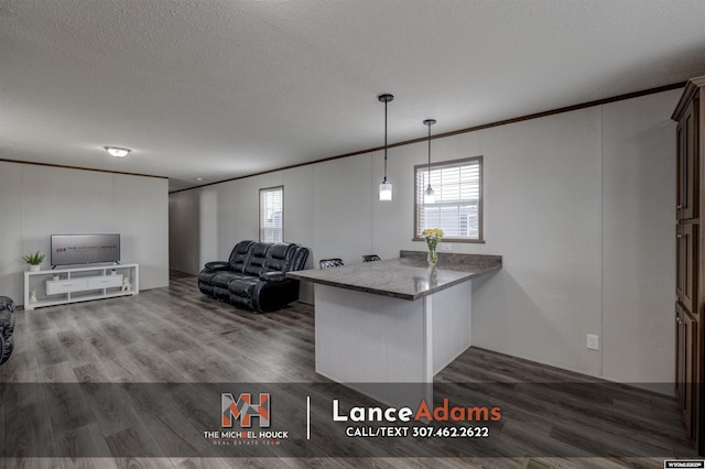 kitchen with dark wood-type flooring, hanging light fixtures, a textured ceiling, ornamental molding, and kitchen peninsula