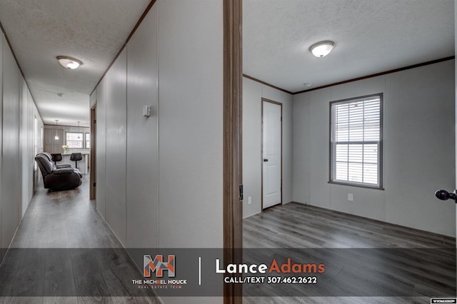 hallway featuring hardwood / wood-style flooring, ornamental molding, and a textured ceiling