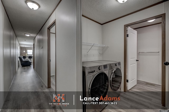laundry area featuring ornamental molding, light hardwood / wood-style floors, washing machine and dryer, and a textured ceiling