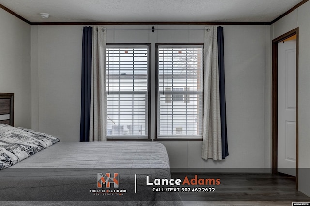 bedroom featuring hardwood / wood-style flooring, ornamental molding, and a textured ceiling