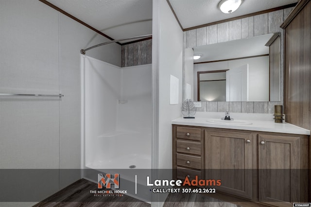 bathroom with vanity, crown molding, wood walls, and walk in shower