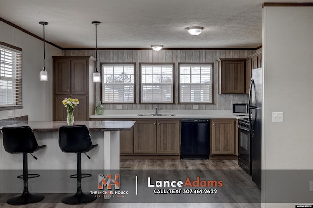 kitchen featuring pendant lighting, black appliances, a kitchen bar, ornamental molding, and kitchen peninsula