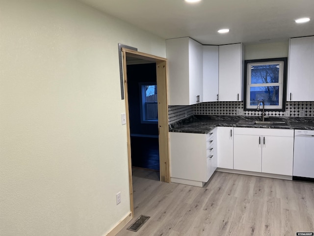 kitchen featuring sink, light wood-type flooring, white dishwasher, decorative backsplash, and white cabinets