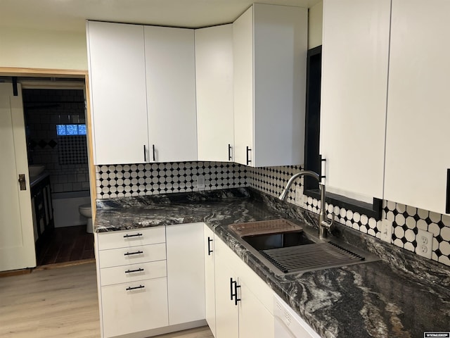 kitchen featuring white cabinetry, sink, and dark stone counters