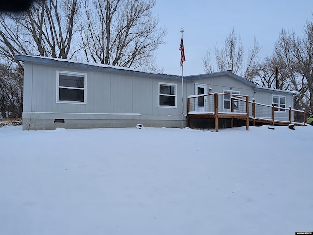 snow covered back of property featuring a wooden deck