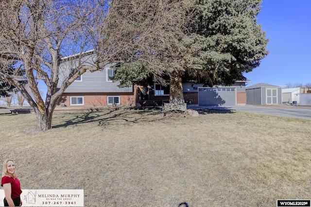 view of front of home featuring driveway, a front lawn, and brick siding