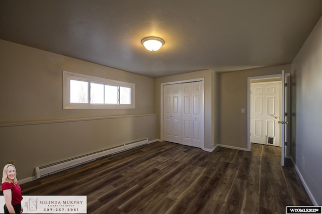 unfurnished bedroom with a closet, dark wood-style flooring, baseboards, and baseboard heating