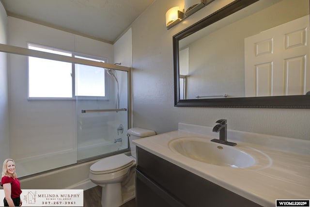 full bath featuring toilet, bath / shower combo with glass door, and vanity