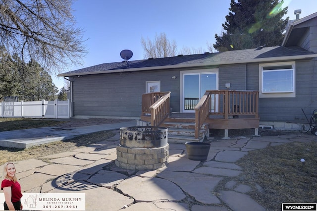 rear view of house with a fire pit, a patio, and fence