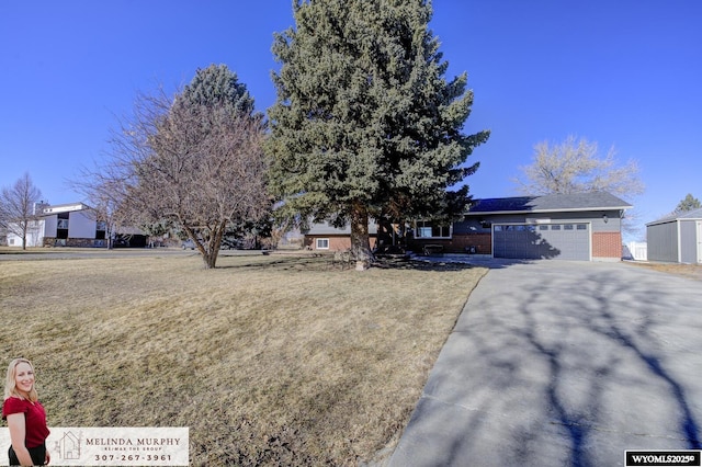 view of front facade featuring a garage, a front yard, brick siding, and driveway