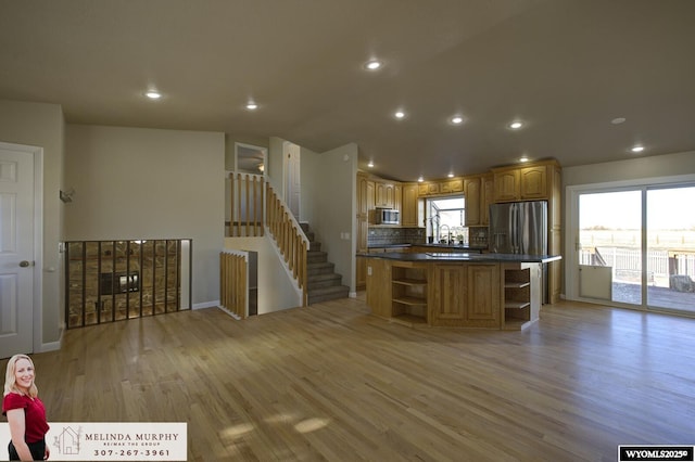 kitchen featuring a center island, light wood finished floors, open shelves, stainless steel appliances, and dark countertops