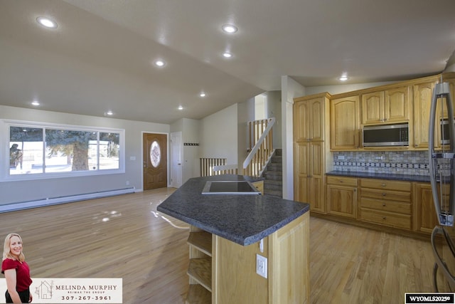 kitchen featuring dark countertops, a kitchen island, stainless steel microwave, refrigerator, and a baseboard heating unit