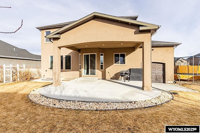 rear view of property with a patio and a trampoline