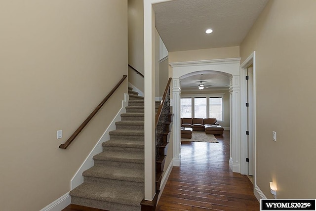 stairway featuring hardwood / wood-style flooring, ceiling fan, and a textured ceiling