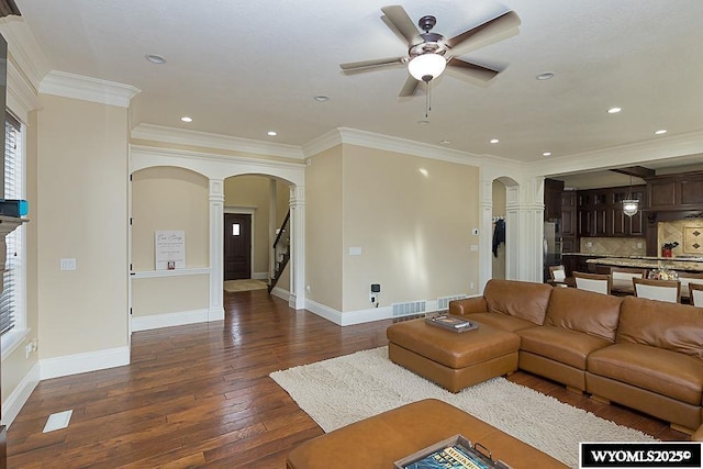 living room featuring crown molding, ceiling fan, dark hardwood / wood-style floors, and ornate columns