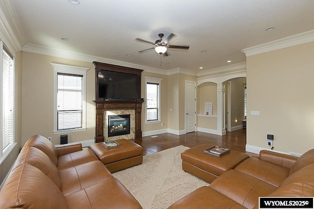 living room with ornamental molding, dark hardwood / wood-style floors, ceiling fan, and a high end fireplace