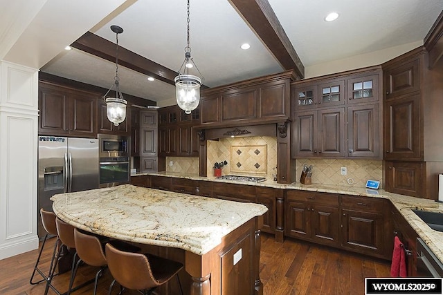 kitchen with appliances with stainless steel finishes, a center island, dark wood-type flooring, and decorative light fixtures