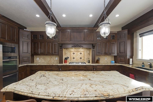 kitchen with hanging light fixtures, sink, dark brown cabinets, and a breakfast bar