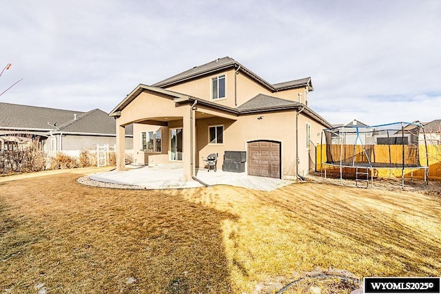 rear view of property with a yard, a trampoline, and a patio area