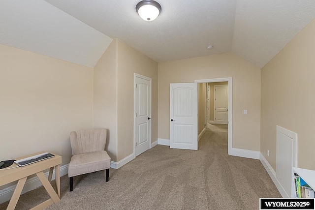 sitting room featuring carpet flooring and vaulted ceiling